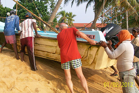 © Reisebüro Seniorenreisen Ein Tourist schiebt auf Sri Lanka mit Einheimischen ein Boot aus dem Wasser