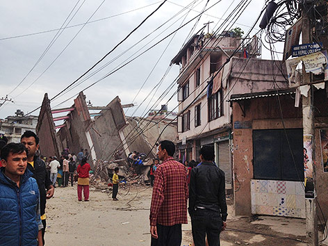Menschen vor den Trümmern eines eingestürzten Gebäudes in Kathmandu