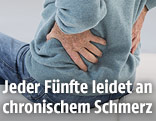 Mann greift sich an den Rücken