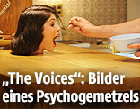 Szene aus "The Voices": Hand füttert Kopf auf einem Tisch