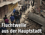 Menschen gehen durch eine verwüstete Straße in Nepal