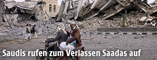 Menschen vor zerstörten Gebäuden in Saada