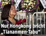 Frau mit Blumen vor Gedenkstätte