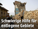 Ein Mann trägt Ziegel vor einem zerstörten Gebäude