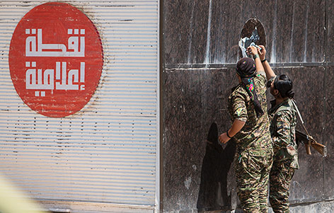 © Reuters/Rodi Said Kurdische Kämpfer in Tal Abjad entfernen ein IS-Sticker auf einer Wand in Tal Abjad