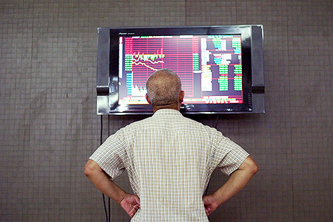 Ein chinesischer Börsenhändler vor einem Monitor mit Börsenkursen