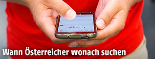 Eine Person hält ein Smartphone mit Google-Suchseite