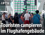 Touristen vor einer Anzeigetafel auf dem Flughafen von Bali