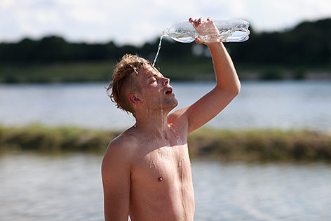 Junger Mann gießt sich Wasser über den Kopf
