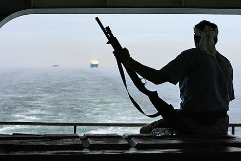 © Reuters/Vivek Prakash Umrisse eines Mannes mit Gewehr, der von einem Boot auf das Meer hinausblickt