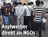 Asylwerber stehen an einem Infopoint