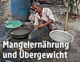 Ein Mann wäscht auf der Straße von Neu Delhi sein Kochgeschirr