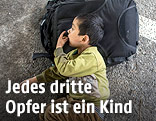 Kind liegt auf einem Rucksack