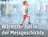 Ein Bub springt durch das Wasser eines Springbrunnens