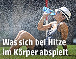 Frau trinkt Wasser auf einer Wiese