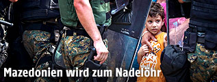 Kind steht zwischen Grenzpolizisten