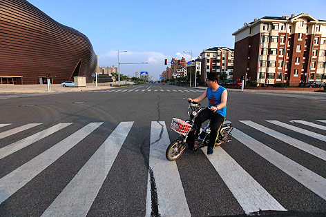 © picturedesk.com/EPA/How Hwee Young Mopedfahrer auf einsamer Straße in Kangbashi