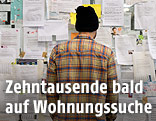 Ein Mann steht vor einer Wand mit Wohnungsanzeigen