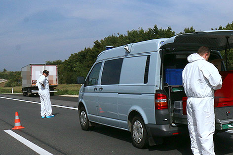 © APA/AP/Ronald Zak (Montage) Mitarbeiter der Spurensicherung neben dem abgestellten Lkw, in dem die Flüchtlinge gefunden wurden