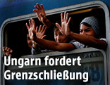 Flüchtlinge winken aus einem österreichischen Zug
