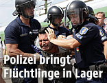 Ungarische Polizisten hatlen einen Flüchtling in der ungarischen Stadt Bicske fest
