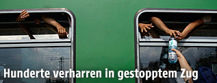 Hände greifen aus dem Zugsfenster nach einer Wasserflasche