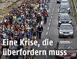 Marschierende Menschenmassen neben fahrenden Autos