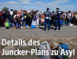 Migranten stehten neben ungarischen Polizisten in einer Schlange