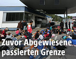 Menschen warten bei der österreichisch-slowenischen Grenzen auf dem Boden