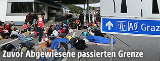 Menschen warten bei der &ouml;sterreichisch-slowenischen Grenzen auf dem Boden