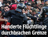 Flüchtlinge und Polizeikräfte an der ungarisch-serbischen Grenze