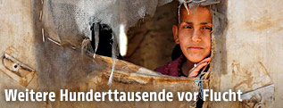 Ein Kind schaut durch ein Fenster im Zelt
