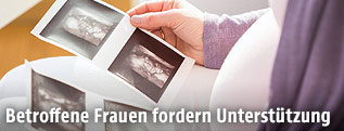 Eine Schwangere blickt auf Ultaschallaufnahmen