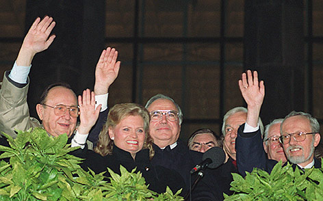 © AP/Archiv/Fritz Reiss Am 3. Oktober 1990 winken der damalige Aussenminister Hans-Dietrich Genscher, Hannelore Kohl, Bundeskanzler Helmut Kohl und der Ex-Premier der DDR, Lothar de Maiziere den jubelnden Menschen zu