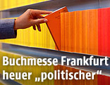 Eine Hand nimmt ein Buch aus einem Bücherregal
