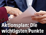 Gipfelteilnehmer halten ein Blatt Papier in der Hand