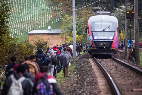 © APA/AFP/Vladimir Simicek Regionalzug fährt neben Hunderten Flüchtlingen