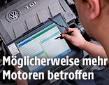 Mechaniker mit Lesegerät über einem VW-Dieselmotor