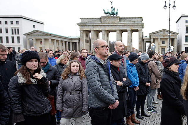 © AP/Michael Sohn Menschen bei einer Gedenkminute am Brandenburger Tor in Berlin