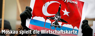 Demonstrant zeigt ein Schild mit einem russischem Flugzeug vor einer türkischen Flagge
