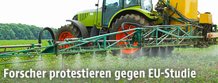 Traktor spr&uuml;ht Pestizide auf einem Acker