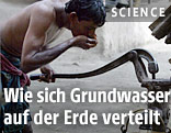 Ein Inder trinkt Wasser aus einem Brunnen gepumpt