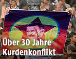 Vermummter Kurde mit Öcalan-Transparent