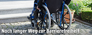 Mann in Rollstul vor Stufen
