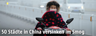 Chinesin mit Schutzmaske auf einem Motorroller