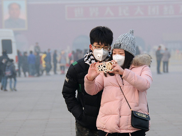 © AP/Imaginechina Ein Paar mit Schutzmasken schießt am Tiananmen-Platz in Peking ein Selfie