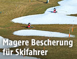 Kleine Kunstschneehaufen unter auf einer Wiese in der Ramsau