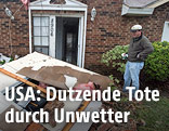 Mann vor zerstörtem Haus