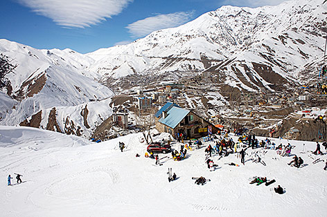 © Corbis/Manca Juvan Schneebedeckte Berge und Skifahrer in Iran