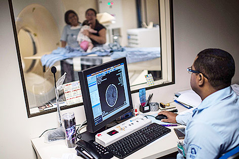 © APA/AFP/Christophe Simoni Ein Arzt in Brasilien blickt auf einen Gehirnscan eines Kindes am Monitor